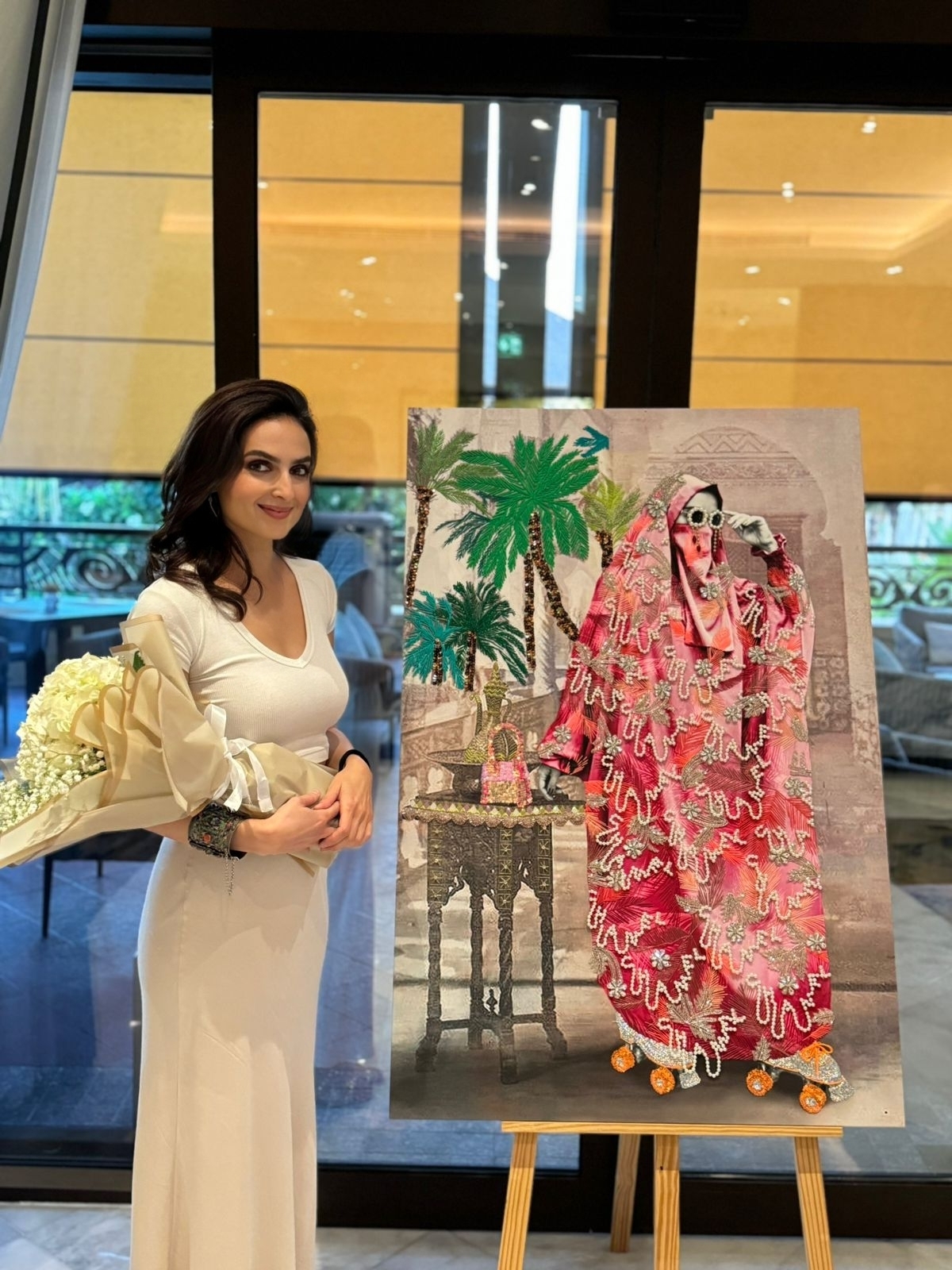 Azaïdé standing beside the commissioned artwork at Sofitel Dubai The Palm